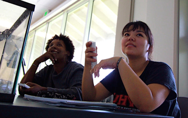 Two students with clickers in the hand ready to vote on the next question. 